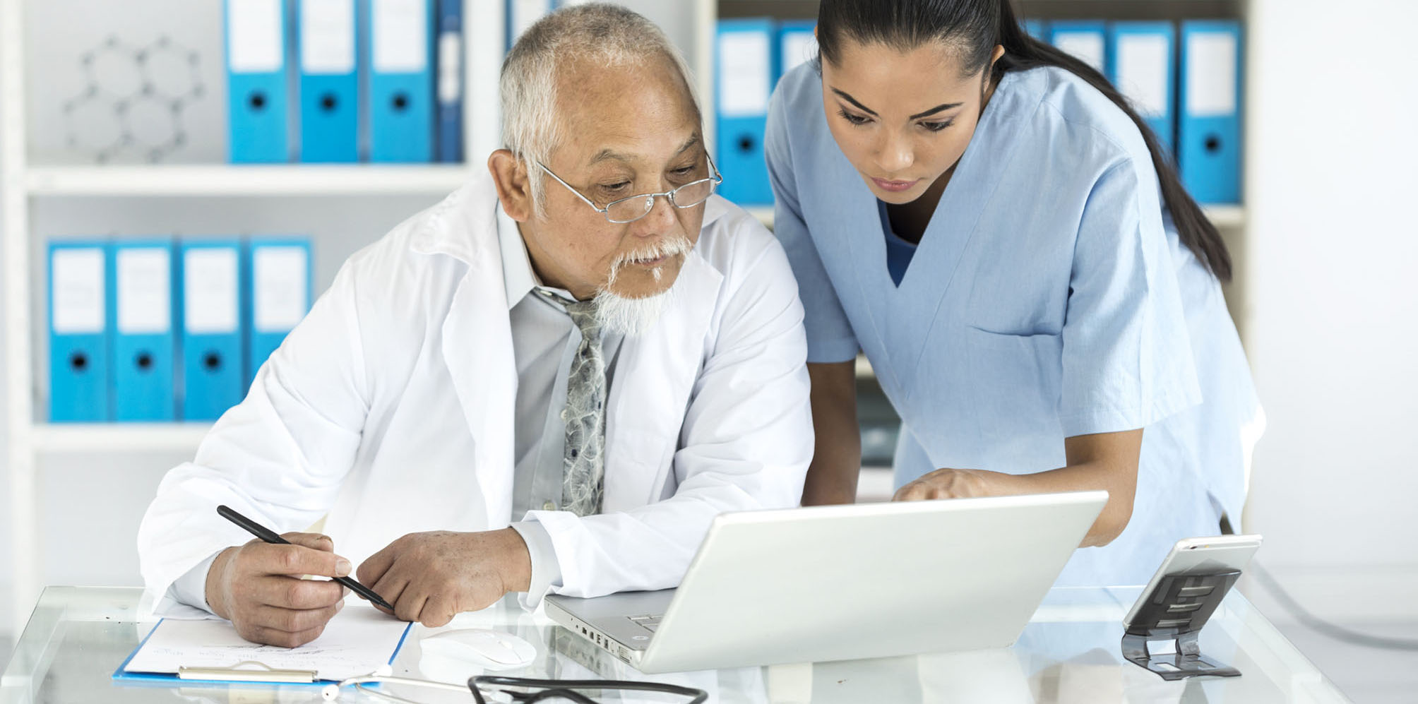 Medical specialists using laptop in cabinet
